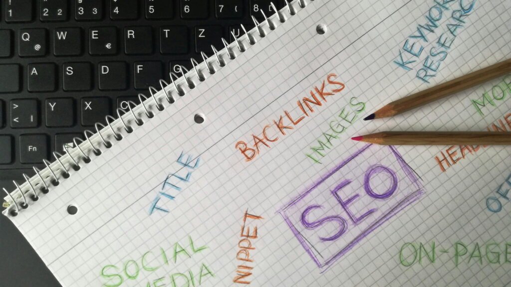 Close‑up of graph paper notebook on keyboard, featuring handwritten SEO concepts like backlinks, keywords, and social media.