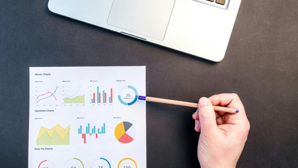 Digital marketing analytics report with charts and graphs beside a laptop, showing SEO performance tracking, traffic analysis, and marketing strategy planning.